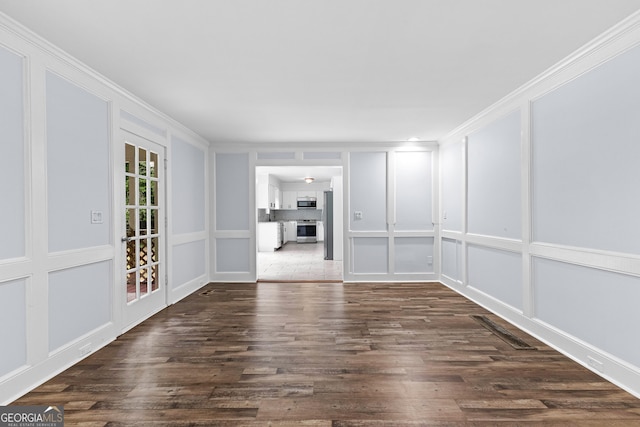 unfurnished room with visible vents, ornamental molding, a decorative wall, and dark wood-type flooring