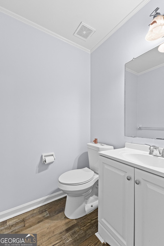 bathroom featuring toilet, wood finished floors, vanity, visible vents, and ornamental molding