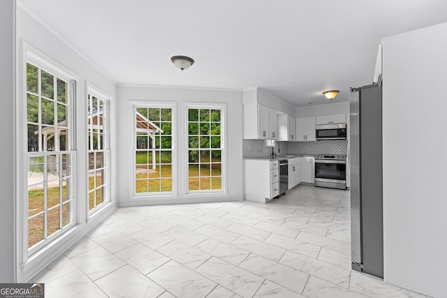 kitchen with marble finish floor, crown molding, light countertops, appliances with stainless steel finishes, and white cabinets