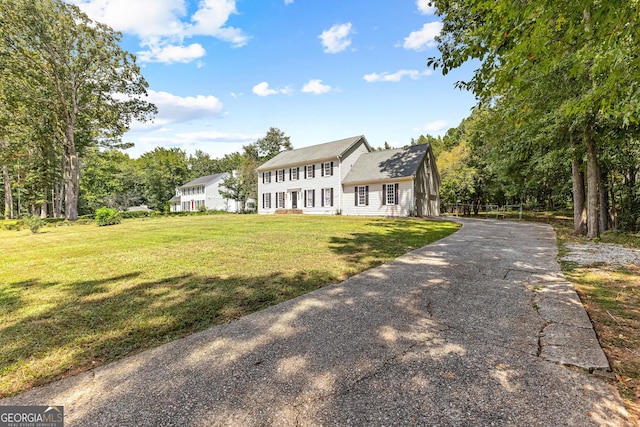 colonial house featuring driveway and a front lawn