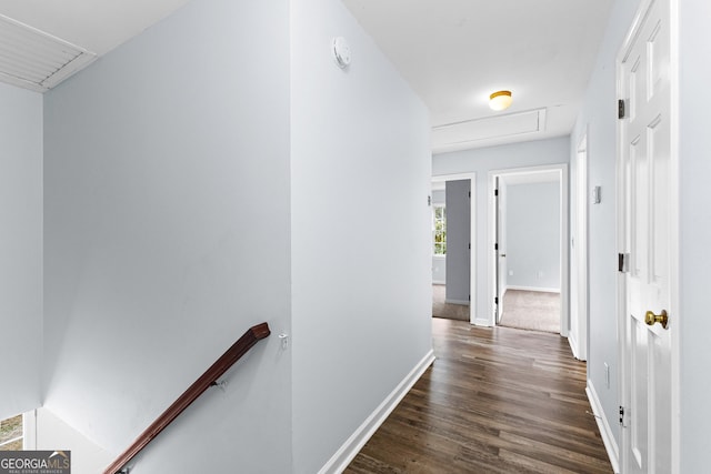 corridor featuring dark wood-type flooring, baseboards, and an upstairs landing