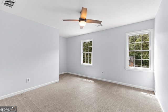 carpeted empty room featuring ceiling fan, visible vents, and baseboards