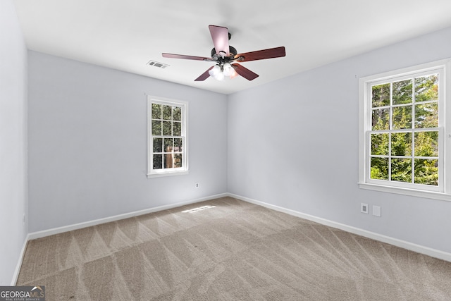 carpeted spare room featuring baseboards, visible vents, and a wealth of natural light