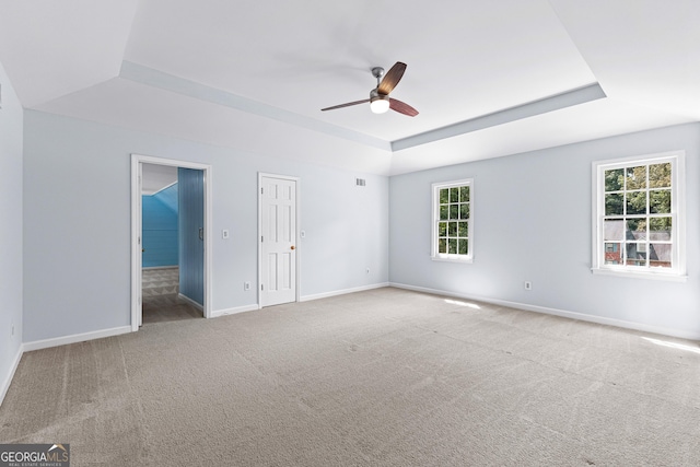 unfurnished bedroom featuring a tray ceiling, carpet flooring, ceiling fan, and baseboards