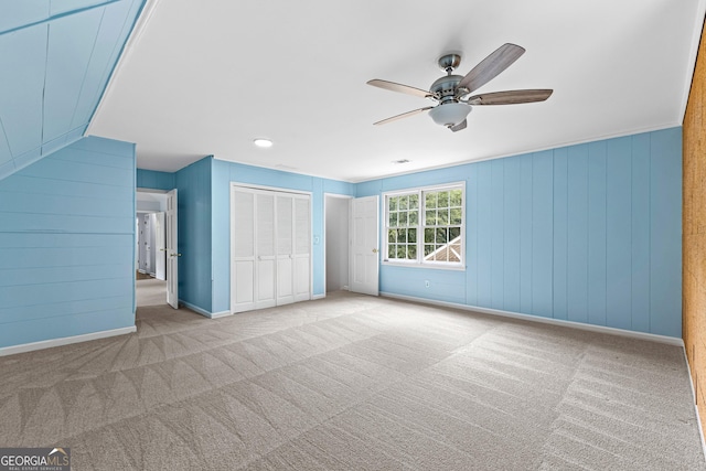 unfurnished bedroom with a ceiling fan, a closet, light carpet, and baseboards