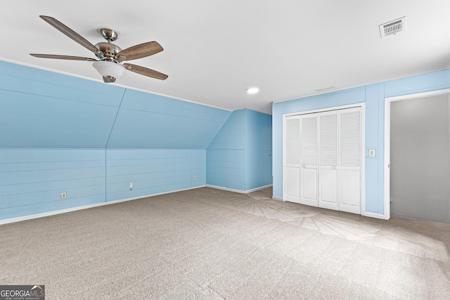 bonus room with wooden walls, visible vents, a ceiling fan, vaulted ceiling, and carpet