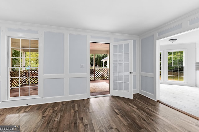 doorway with crown molding, a decorative wall, and dark wood-style flooring