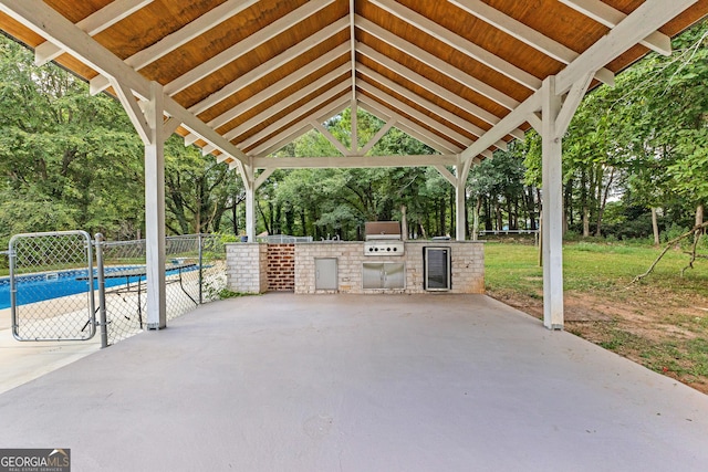 view of patio featuring a gazebo, a grill, fence, exterior kitchen, and an outdoor pool