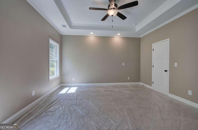 carpeted spare room with ceiling fan, a raised ceiling, and ornamental molding