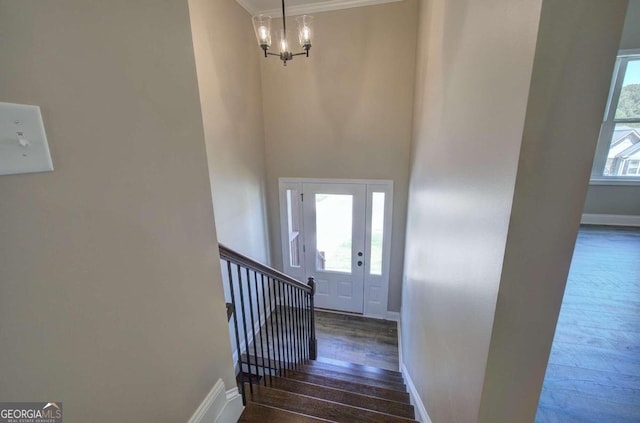 stairs with an inviting chandelier, baseboards, and hardwood / wood-style flooring