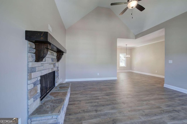 unfurnished living room with a stone fireplace, ceiling fan with notable chandelier, baseboards, and wood finished floors