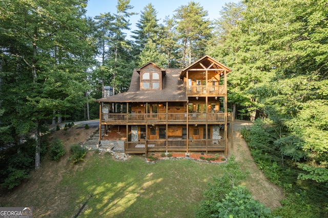 back of house featuring a lawn and a balcony