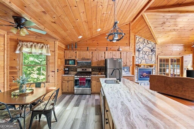 kitchen featuring wooden ceiling, wood-type flooring, hanging light fixtures, stainless steel appliances, and wooden walls