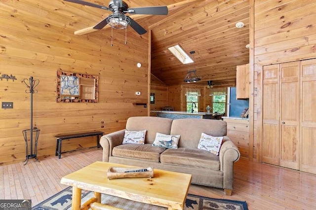 living room with wood walls, ceiling fan, wooden ceiling, and light hardwood / wood-style flooring