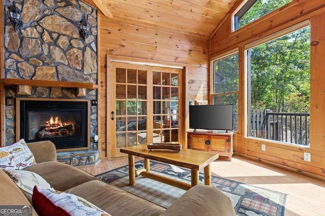 living room featuring vaulted ceiling, wood walls, a stone fireplace, wood ceiling, and hardwood / wood-style flooring