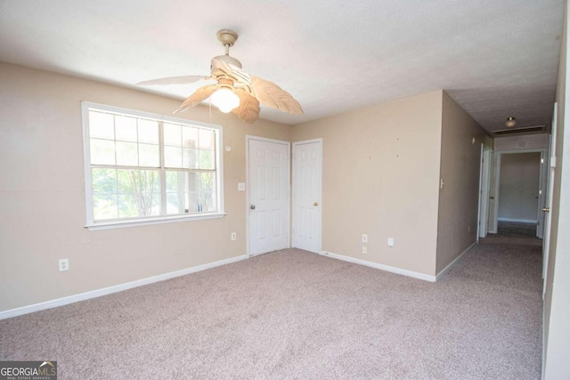 empty room with ceiling fan, light colored carpet, and a textured ceiling