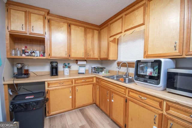 kitchen featuring sink, a textured ceiling, and light hardwood / wood-style flooring