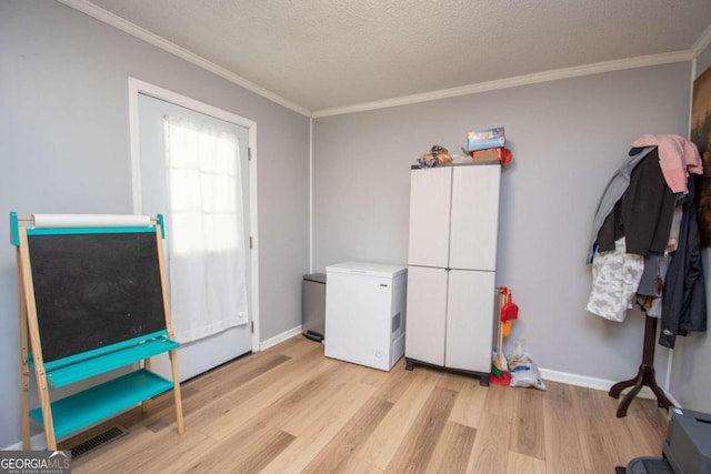 interior space featuring light wood-type flooring, crown molding, and a textured ceiling