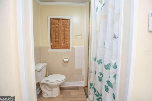 bathroom featuring hardwood / wood-style floors, crown molding, tile walls, toilet, and a shower with curtain