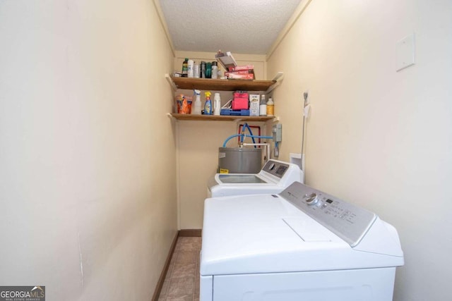 laundry area with light tile patterned floors, a textured ceiling, and washing machine and clothes dryer