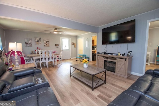 living room featuring a textured ceiling, light hardwood / wood-style flooring, ceiling fan, and crown molding