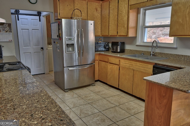 kitchen featuring black appliances, sink, light tile patterned floors, and a barn door