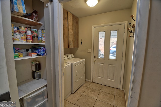 laundry area with cabinets, light tile patterned floors, and washer and clothes dryer