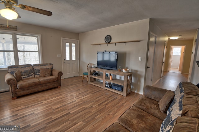 living room featuring a healthy amount of sunlight, ceiling fan, and wood-type flooring