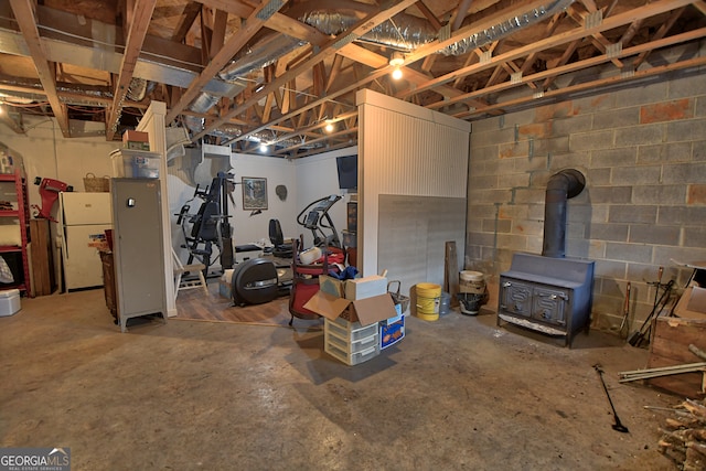 basement with white fridge and a wood stove