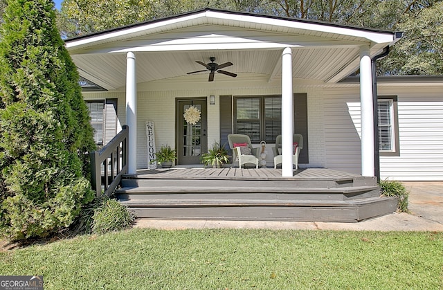 entrance to property featuring a porch, a lawn, and ceiling fan