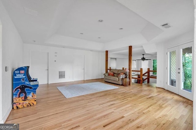 sitting room featuring a raised ceiling, french doors, ceiling fan, and light hardwood / wood-style floors