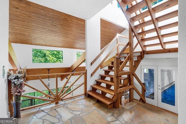 stairway with a towering ceiling, wooden ceiling, and french doors