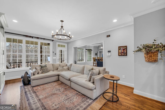 living room with hardwood / wood-style floors, a notable chandelier, and ornamental molding