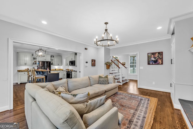 living room with dark wood-type flooring, a notable chandelier, and ornamental molding