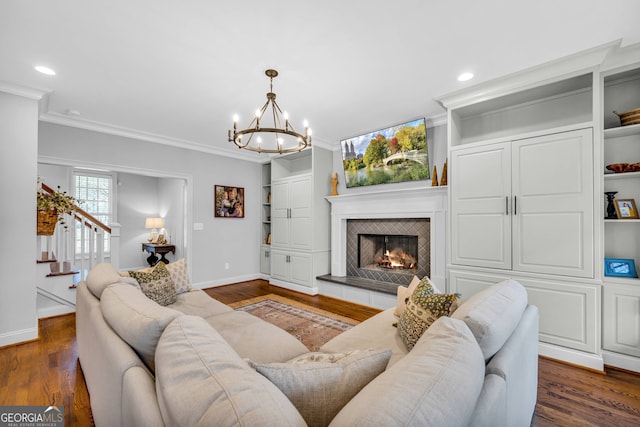 living room featuring a fireplace, dark hardwood / wood-style floors, an inviting chandelier, and crown molding