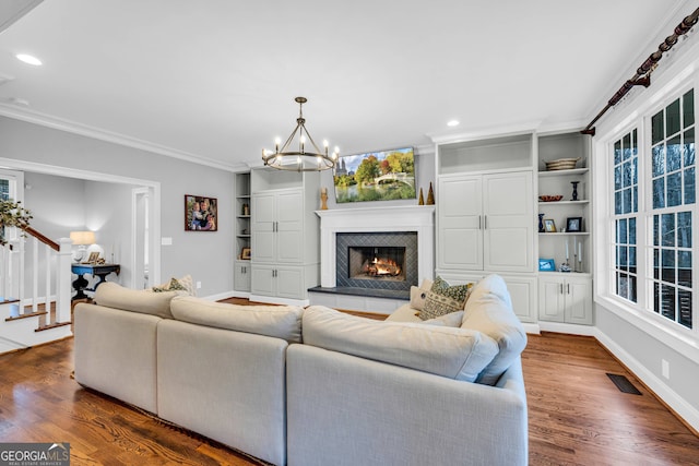 living room featuring ornamental molding, a chandelier, a tile fireplace, and dark hardwood / wood-style floors