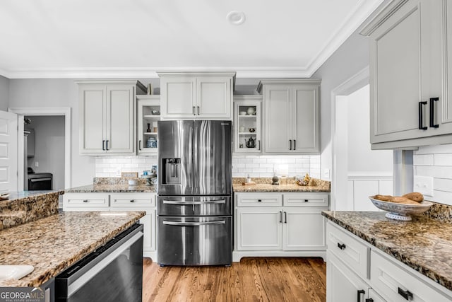 kitchen with ornamental molding, appliances with stainless steel finishes, backsplash, and light hardwood / wood-style floors