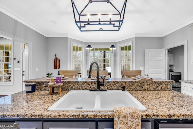 kitchen with hanging light fixtures, ornamental molding, a center island with sink, and sink