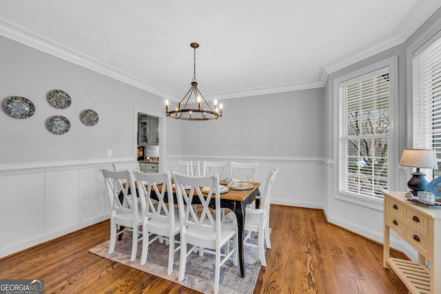 dining area featuring an inviting chandelier, ornamental molding, and hardwood / wood-style flooring