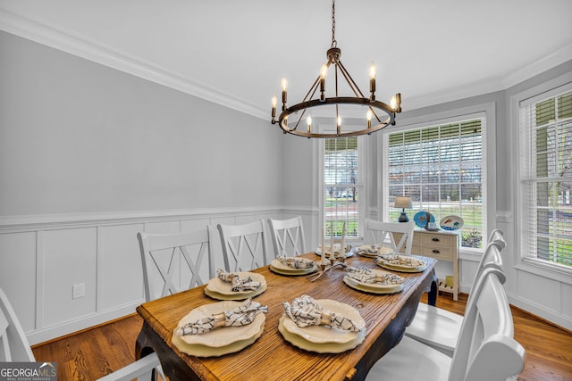 dining room with crown molding, a wealth of natural light, hardwood / wood-style floors, and an inviting chandelier