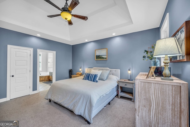 carpeted bedroom featuring a raised ceiling, ceiling fan, and ensuite bath