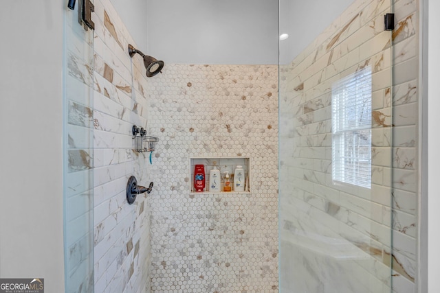 bathroom with a tile shower and plenty of natural light