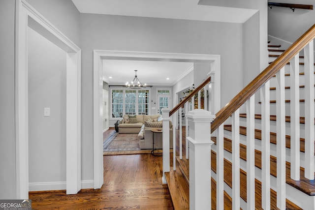 entrance foyer with ornamental molding, dark hardwood / wood-style flooring, and a notable chandelier