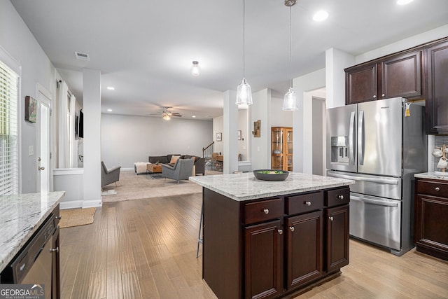 kitchen with light wood finished floors, appliances with stainless steel finishes, open floor plan, and dark brown cabinets