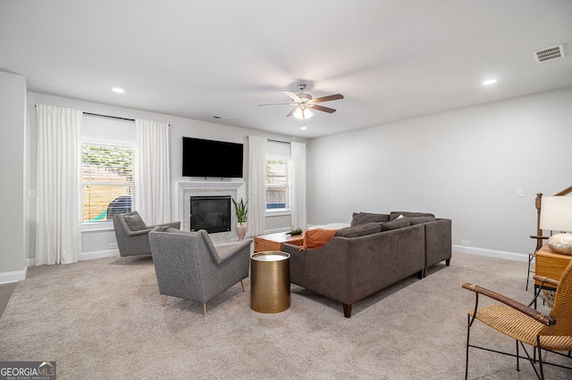 living room with a glass covered fireplace, visible vents, plenty of natural light, and light carpet