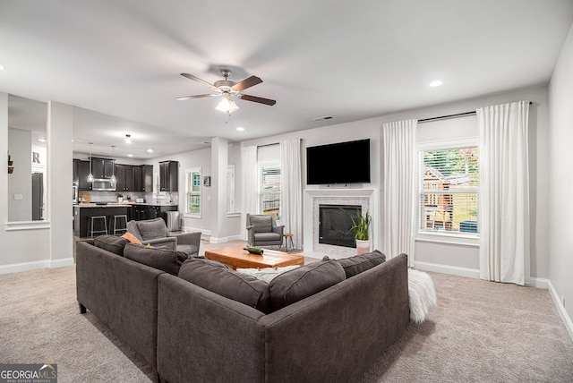 living area featuring a fireplace with flush hearth, light carpet, visible vents, and baseboards