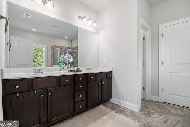 bathroom featuring visible vents, a sink, a shower stall, and double vanity