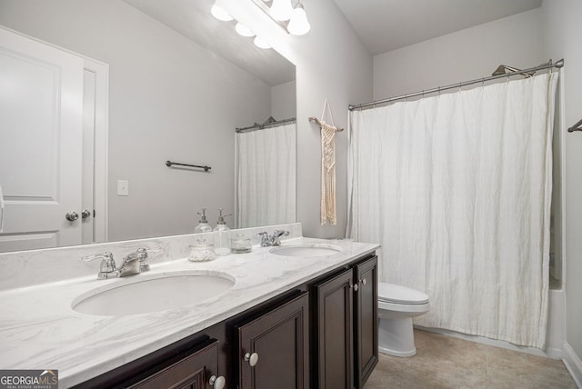 full bath featuring toilet, double vanity, a sink, and tile patterned floors