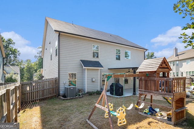 rear view of house featuring a fenced backyard, a yard, a patio area, central AC, and a playground