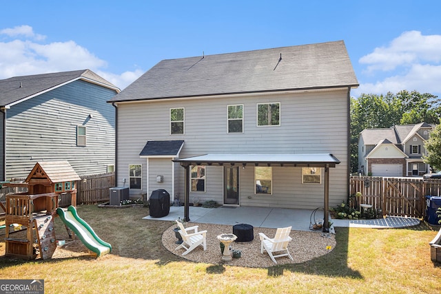 rear view of property with a playground, a patio, a lawn, central AC, and a fenced backyard